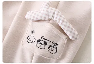 Detail of baby knit trousers featuring a funny dogs pocket and checkered decoration