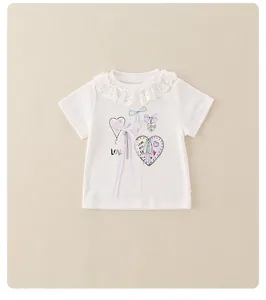 Detail van wit baby shirt voor meisjes met kant kraag en strik met hartjes patroon