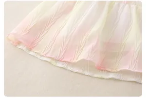 Detail view of girl's dress with pleated gradient chiffon fabric in pastel pink and yellow