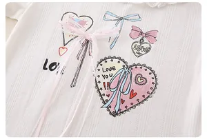 Detail van katoenen top voor meisjes met hartprint, kant en roze tule strik decoratie