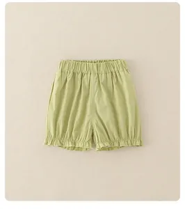 Dettaglio di pantaloncini da bambina verde chiaro con elastico in vita e bordi con volant