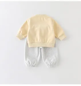 Platliggende katoenen babyset met geel shirt met lange mouwen en grijze trekkoordbroek