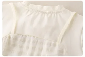 Dettaglio del top in maglia di cotone crema per bambina con scollo a costine e tessuto