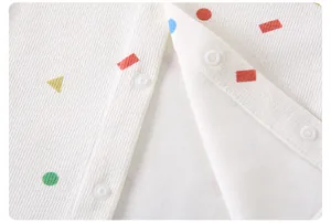 Close-up of baby romper fabric with colorful geometric patterns and white snap buttons