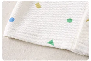 Detailed macro view of children's waffle knit fabric with colorful geometric prints and button