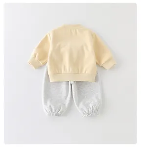 Detail van tweedelige baby-set met gele sweatshirt en grijze joggingbroek van katoen