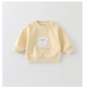 Detail van baby-sweatshirt met geribbelde manchetten en puppy-borduurwerk op gele stof