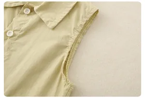 Detail view of khaki sleeveless top collar and white buttons with fine cotton texture