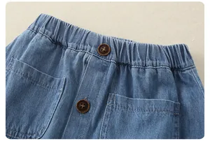 Detail of girls' blue denim skirt with elastic waist, wood buttons and utility pockets