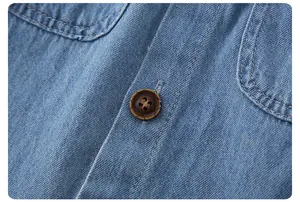 Detailed close-up of light blue denim fabric texture and brown vintage button on summer top