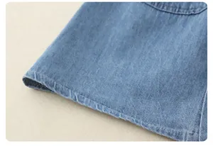 Detailed close-up of light blue denim fabric texture and double-stitched seam craftsmanship