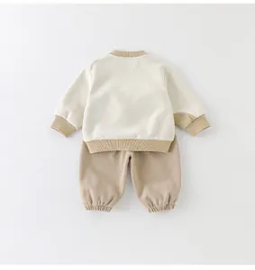 Detail eines Baby-Zweiteilers mit cremefarbenem Sweatshirt und khakifarbener Jogginghose