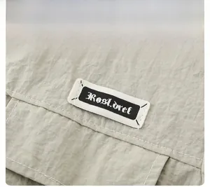 Close-up of khaki utility fabric showing woven label and white contrast stitching