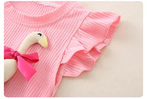 Dettaglio top rosa con maniche a volant, cigno in peluche 3D e fiocco per neonata