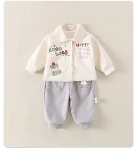 Détail de la veste bébé beige avec motif chien et jogging gris ensemble deux pièces