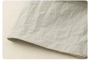 Macro shot of sage green cotton fabric with neat white stitching and natural texture