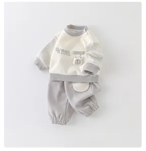 Detail of baby cotton two-piece set featuring striped sleeves and cute 3D bear pocket