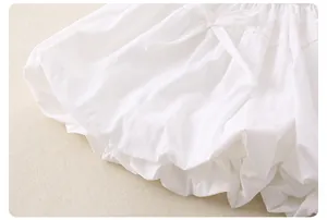 Dettaglio dei pantaloncini a sbuffo in cotone bianco per bimba con fiocco e volant