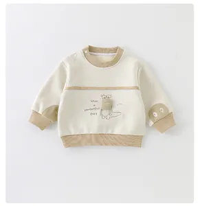 Detail eines Baby-Sweatshirts in Beige mit Krokodil-Stickerei und Schulterknöpfen