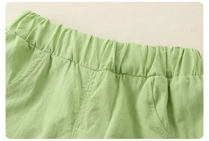 Detail of light green girls' cotton shorts showing elastic waist and side pockets
