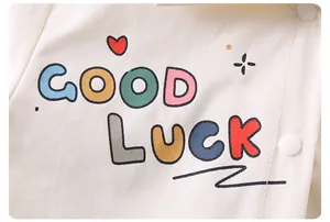 Détail de l'ensemble bébé en coton avec imprimé GOOD LUCK et boutons-pression blancs
