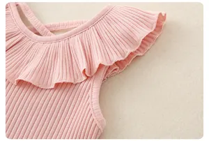 Dettaglio del gilet in cotone rosa a coste con volant e spalline incrociate per neonata