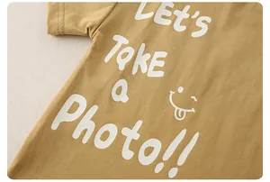 Close-up of ginger yellow cotton kids T-shirt with fine stitching and letter print
