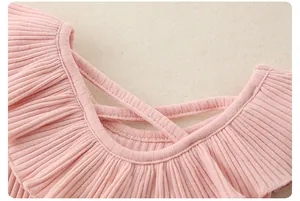 Dettaglio di tessuto rosa a costine con colletto a balze e lacci decorativi chic