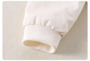 Vue détaillée des poignets côtelés crème et du tissu en coton doux pour tenue de bébé