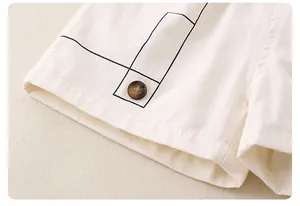 Detailed close-up of white cotton shorts featuring geometric print and marble resin button