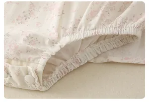 Dettaglio di pagliaccetto neonata a fiori rosa con gambe elastiche e bottoni automatici