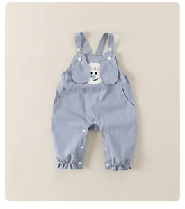 Detail der hellblauen Baby-Latzhose mit süßem Cartoon-Gesicht und Rüschen