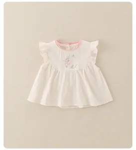 Détail du haut en coton pour bébé avec dentelle rose et lettre C brodée sur le buste