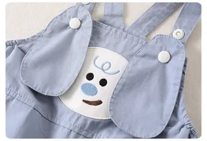 Detail von Baby-Latzhose mit 3D-Hundeohren und süßer Welpen-Stickerei auf blauer Baumwolle