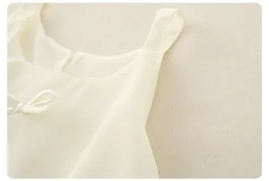 Détail du haut crème pour bébé avec nœud en satin et coutures délicates sur les bretelles