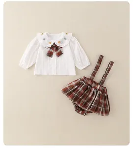 Detail van babymeisjes JK-outfit met geborduurde Peter Pan-kraag en geruite bretelshort