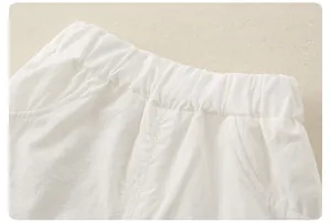 Dettaglio di pantaloncini bianchi in cotone e lino per bambina con vita elastica e tasche