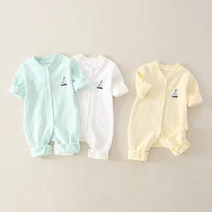 Detailed close-up of ribbed cotton baby rompers in mint green, cream, and yellow colors