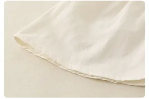 Détail du tissu en coton crème avec pois jacquard et finitions de couture soignées