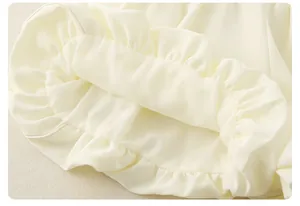 Détail de volants blanc crème sur tenue d'été pour fille en tissu mousseline doux