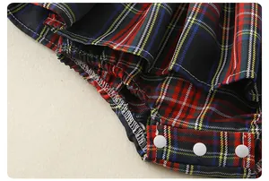 Detail van geruite babyjurk met witte drukknopen en elastische beenopeningen
