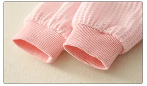 Close-up of pink waffle knit baby onesie cuffs with soft ribbed texture and fine stitching