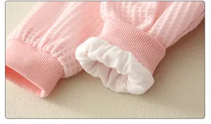 Detailed macro view of pink waffle knit baby onesie cuffs with soft white inner lining