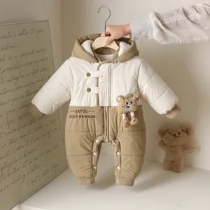 Detail of baby winter romper featuring quilted fabric, hood, and 3D plush bear ornament