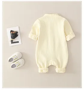 Detailed view of beige ribbed cotton long sleeve baby romper with white crib shoes
