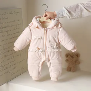 Close-up of pink quilted baby snowsuit with swan embroidery and ruffled details