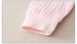 Detailed close-up of pink ribbed cotton infant romper cuffs with white snap buttons