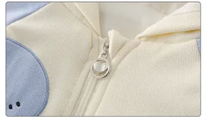 Detail of baby cotton onesie featuring a silver heart-shaped zipper and soft knit fabric