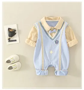 Detail view of baby romper featuring a blue bowtie and elegant crest applique design