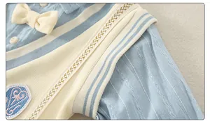 Detail of baby cotton romper with knit vest, striped collar and embroidered badge